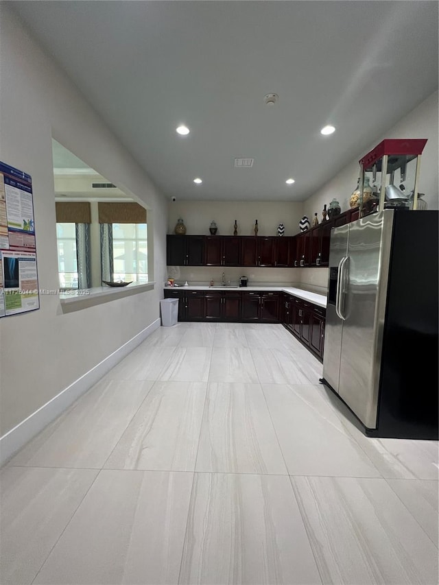 kitchen featuring sink, light tile patterned floors, dark brown cabinetry, and stainless steel fridge with ice dispenser