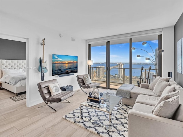 living room with expansive windows and light hardwood / wood-style flooring