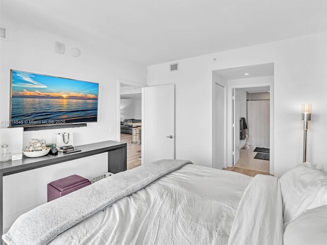 bedroom with ensuite bath and light hardwood / wood-style floors