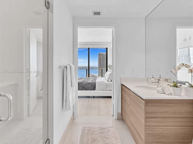 bathroom with vanity, a shower with door, tile patterned floors, and a water view