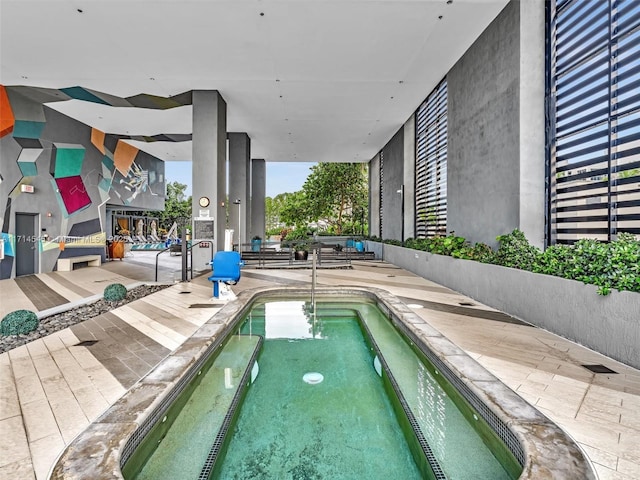 view of pool with a hot tub and a patio area