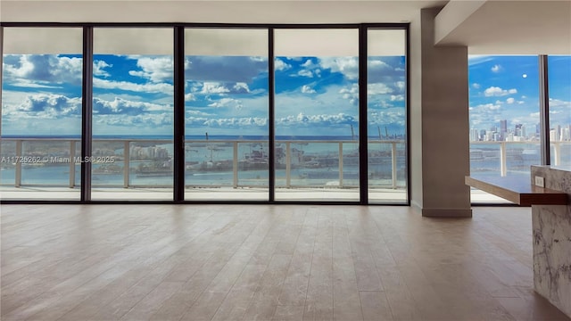 spare room featuring hardwood / wood-style flooring, a wall of windows, and a water view