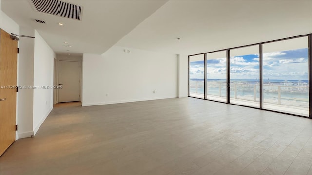 empty room with floor to ceiling windows and light wood-type flooring