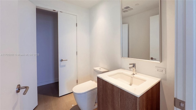 bathroom with toilet, wood-type flooring, and vanity