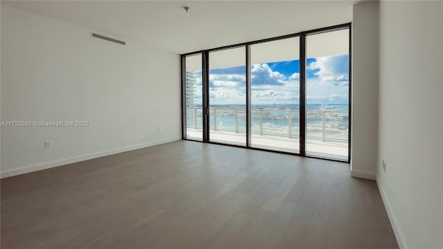 unfurnished room featuring floor to ceiling windows and wood-type flooring