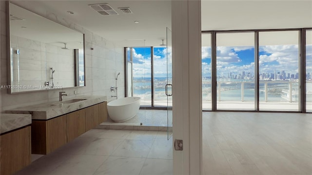 bathroom featuring vanity, a water view, plus walk in shower, and expansive windows