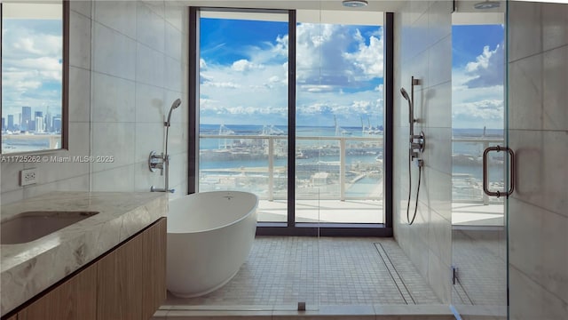 bathroom with a water view, vanity, tile patterned floors, floor to ceiling windows, and shower with separate bathtub