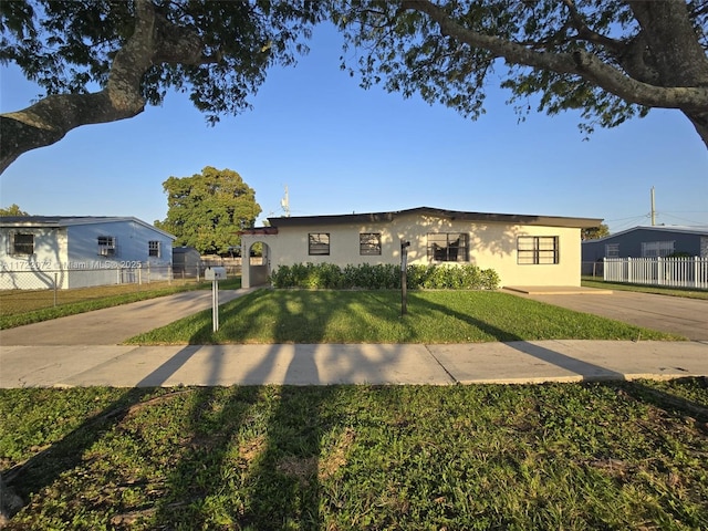 view of front of house with stucco siding, a front yard, and fence