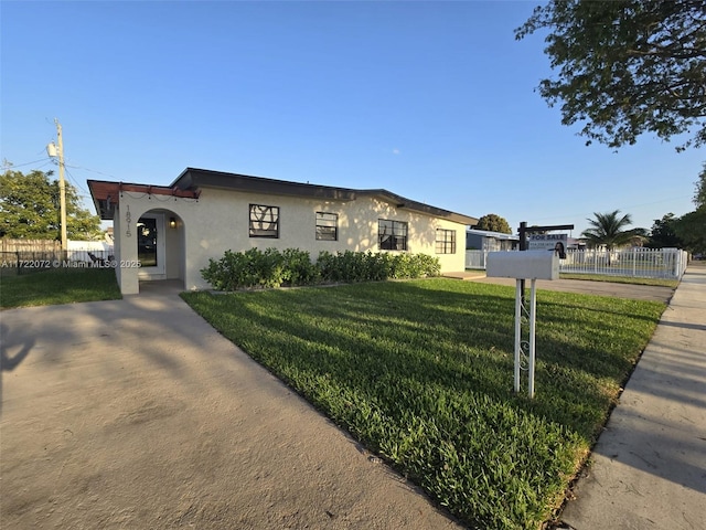 view of front of home featuring stucco siding, a front lawn, and fence