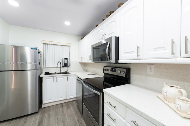 kitchen featuring white cabinetry, appliances with stainless steel finishes, decorative backsplash, sink, and light hardwood / wood-style flooring