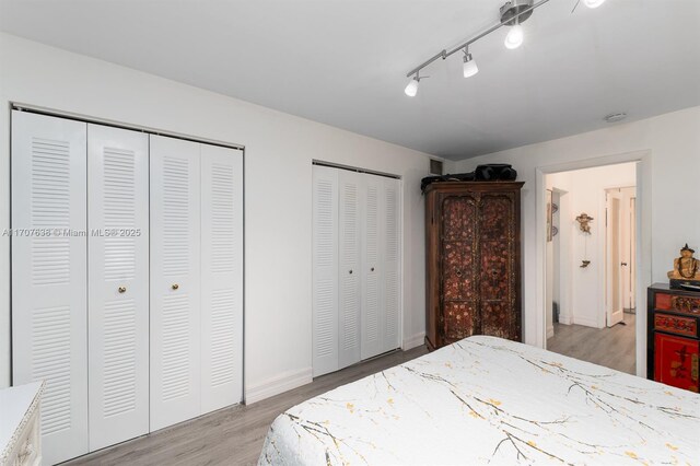 bedroom with two closets and light hardwood / wood-style floors