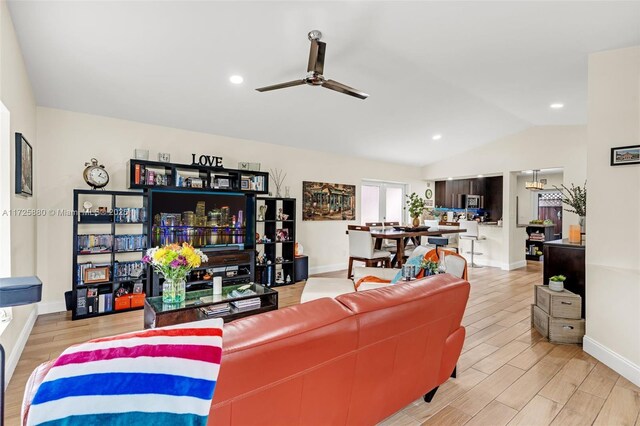 living room featuring ceiling fan, vaulted ceiling, and light hardwood / wood-style flooring