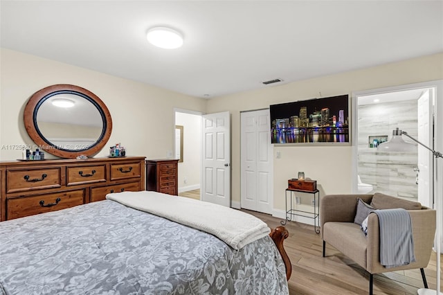 bedroom with a closet, visible vents, ensuite bathroom, light wood-type flooring, and baseboards