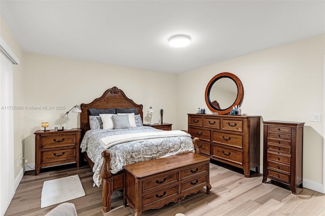 bedroom featuring light wood finished floors and baseboards