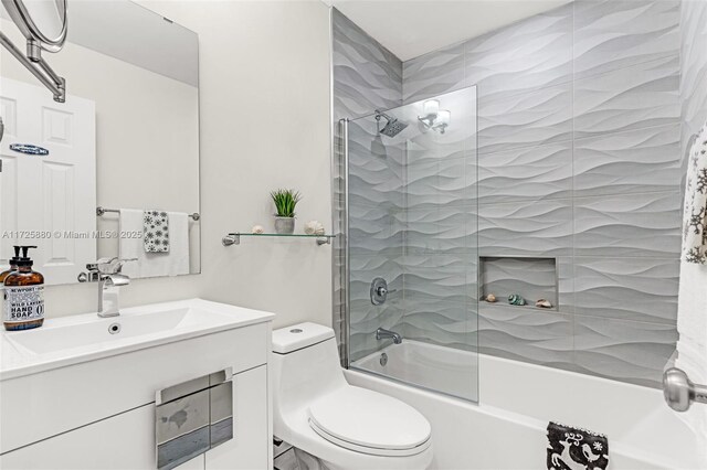 full bathroom featuring tiled shower / bath, vanity, and toilet