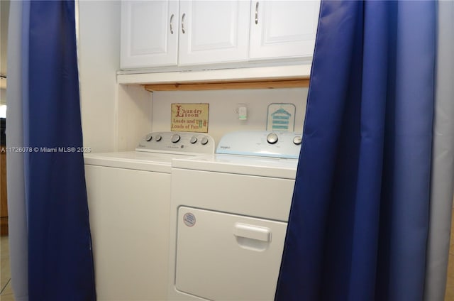 washroom with washer and dryer and cabinets