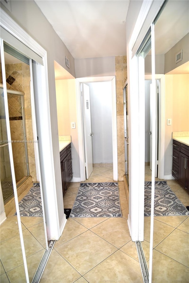 bathroom featuring tile patterned flooring, a shower with shower door, and vanity