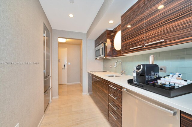 kitchen with sink, stainless steel appliances, decorative backsplash, and dark brown cabinetry