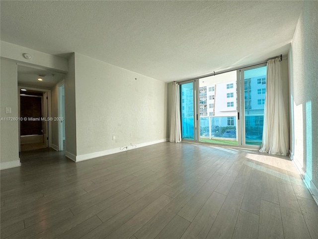 spare room with a wall of windows, dark hardwood / wood-style flooring, and a textured ceiling