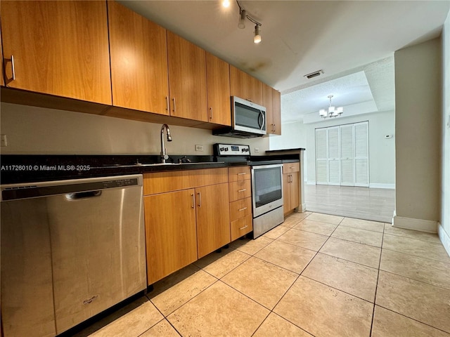 kitchen with appliances with stainless steel finishes, light tile patterned floors, a notable chandelier, a textured ceiling, and sink