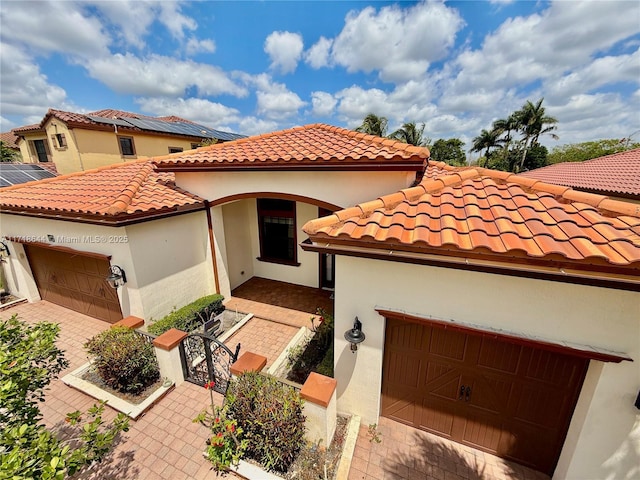 mediterranean / spanish home with an attached garage, a tile roof, and driveway