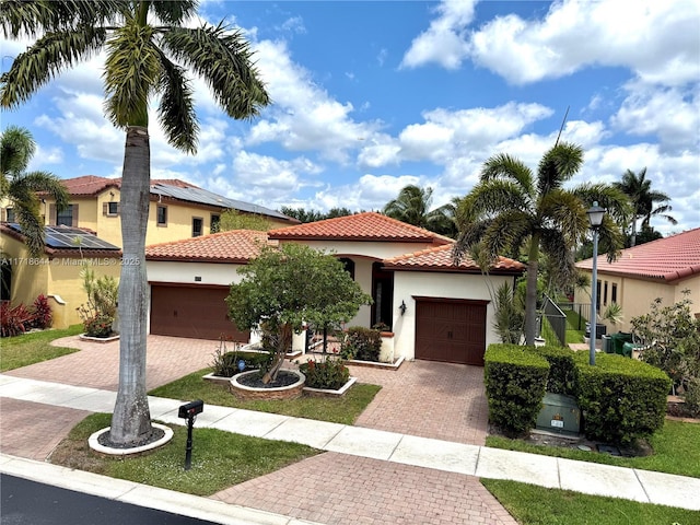 mediterranean / spanish-style home featuring an attached garage, decorative driveway, and a tiled roof