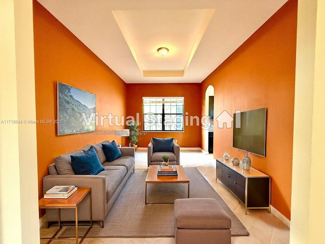 living room with baseboards and a raised ceiling