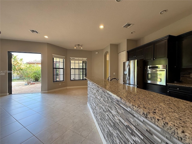 kitchen with light stone counters, stainless steel appliances, visible vents, and light tile patterned floors