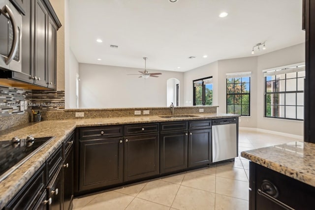 kitchen featuring light stone counters, a sink, light tile patterned flooring, appliances with stainless steel finishes, and ceiling fan