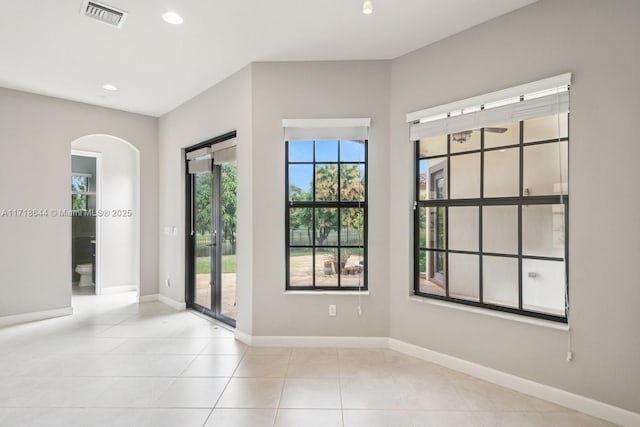 empty room with visible vents, recessed lighting, arched walkways, tile patterned flooring, and baseboards