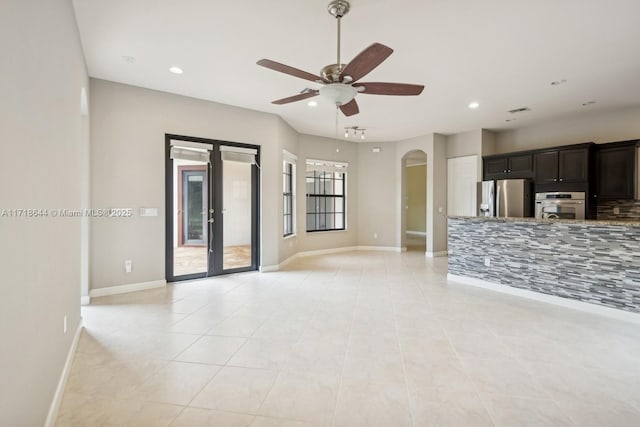 unfurnished living room featuring baseboards, arched walkways, a ceiling fan, and recessed lighting