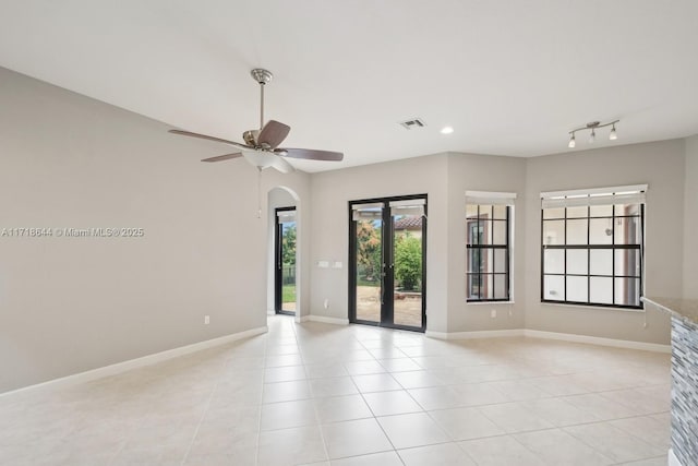 unfurnished room featuring visible vents, arched walkways, baseboards, and light tile patterned flooring