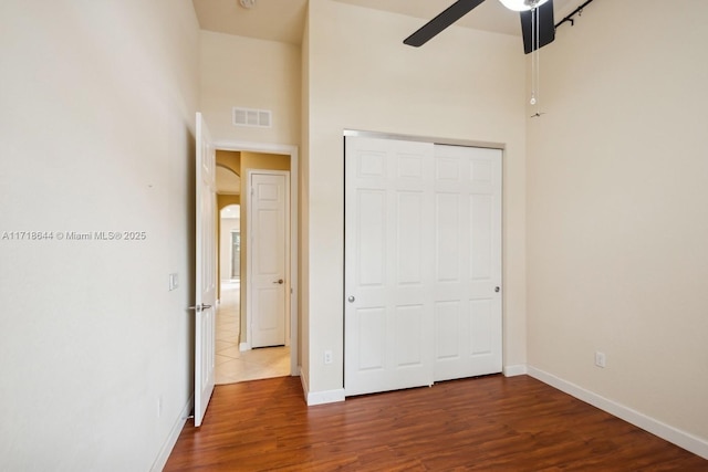 unfurnished bedroom with visible vents, wood finished floors, a closet, baseboards, and ceiling fan