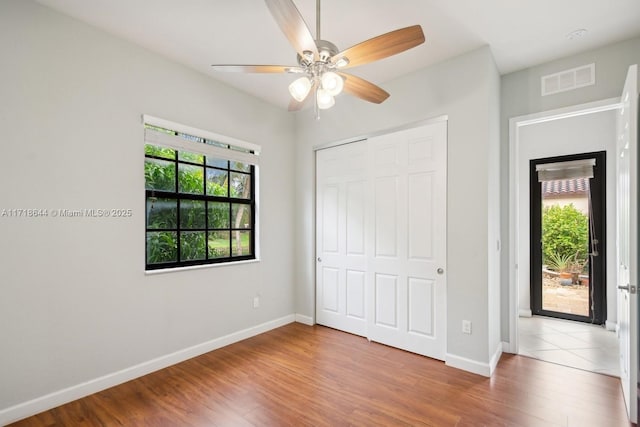 unfurnished bedroom featuring wood finished floors, visible vents, a closet, and baseboards