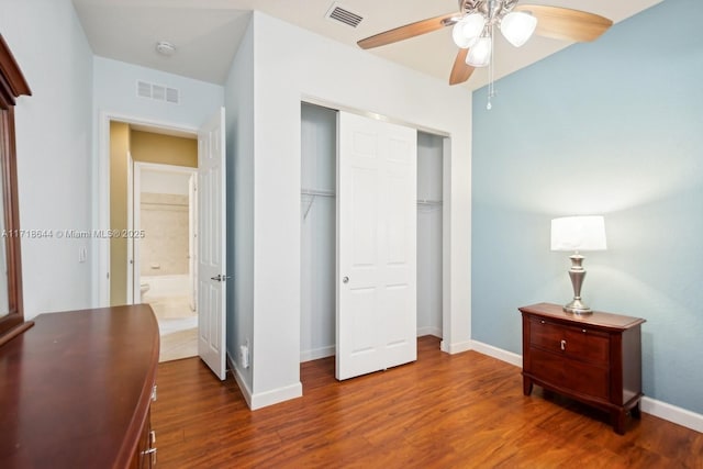 bedroom with wood finished floors, visible vents, a closet, and baseboards