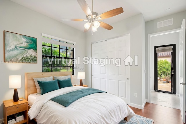 bedroom with wood finished floors, visible vents, a closet, baseboards, and ceiling fan