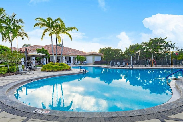 community pool with a patio and fence