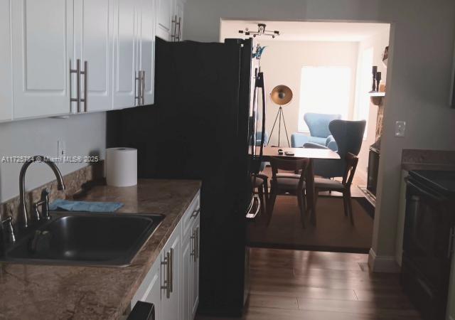 kitchen with white cabinets, dark wood-type flooring, dark stone countertops, and sink