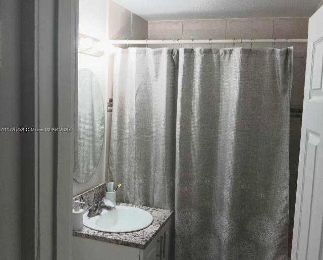 bathroom featuring walk in shower and vanity