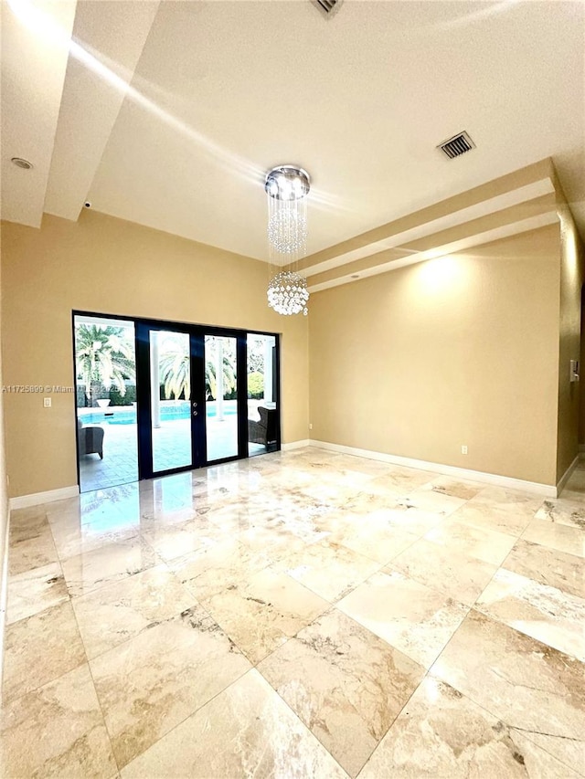 empty room featuring french doors and a chandelier