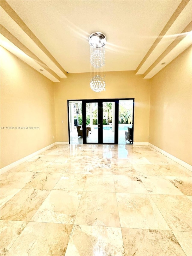 unfurnished room with french doors and a chandelier