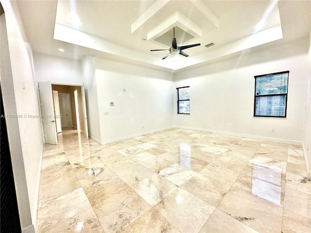 empty room featuring a raised ceiling and ceiling fan