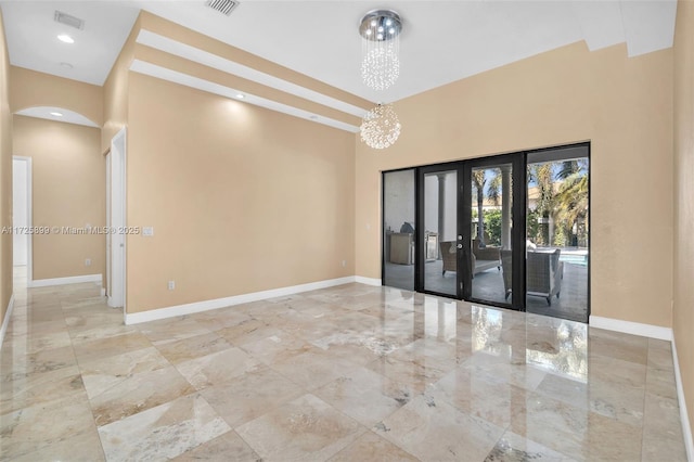 unfurnished room with an inviting chandelier and french doors