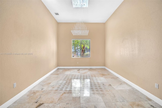 unfurnished room with a chandelier