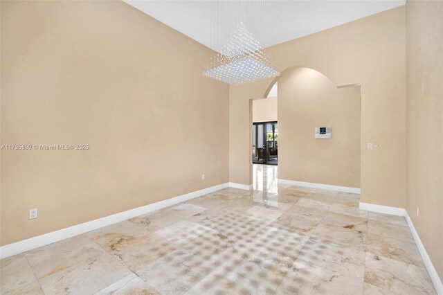 spare room featuring a towering ceiling and a chandelier