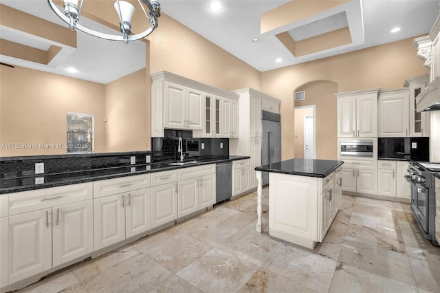 kitchen with high end appliances, tasteful backsplash, a kitchen island, and white cabinets