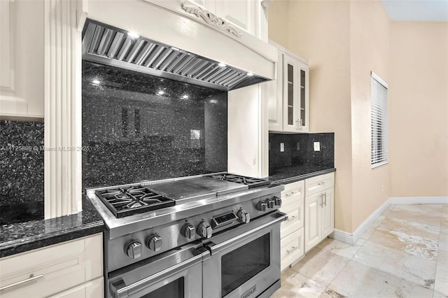 kitchen with custom exhaust hood, tasteful backsplash, white cabinetry, double oven range, and dark stone counters