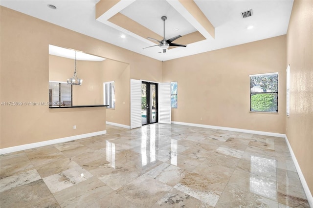 unfurnished room with a high ceiling, plenty of natural light, and ceiling fan with notable chandelier