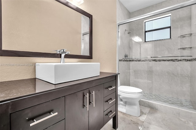 bathroom with a shower with door, vanity, and toilet