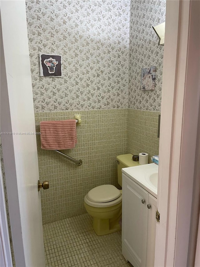 bathroom featuring toilet, vanity, tile patterned flooring, and tile walls